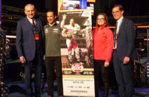 PRI President Jamie Meyer, Helio Castroneves, ticket designer Mandy Walsh and IMS President Doug Boles unveil the 2022 Indianapolis 500 ticket. [Mark Theisen Photo]